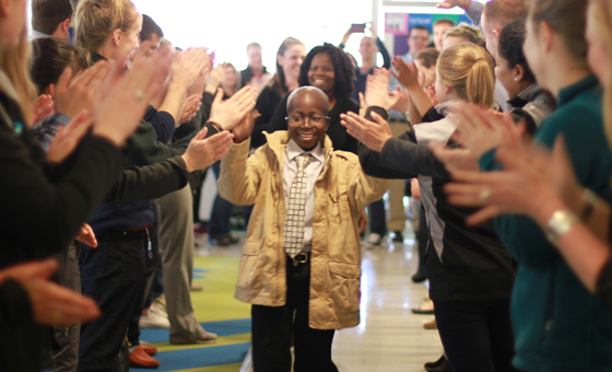 Pediatric patient walking down the bluebird bio hallway high-fiving employees lined up on either side