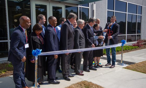 A group of bluebird bio employees participating in a celebratory ribbon cutting ceremony in front of a building